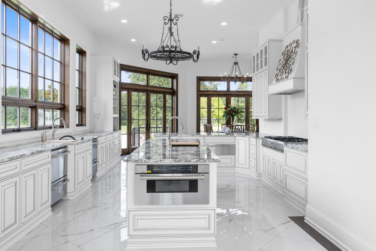 White luxury kitchen with marble island and chandelier