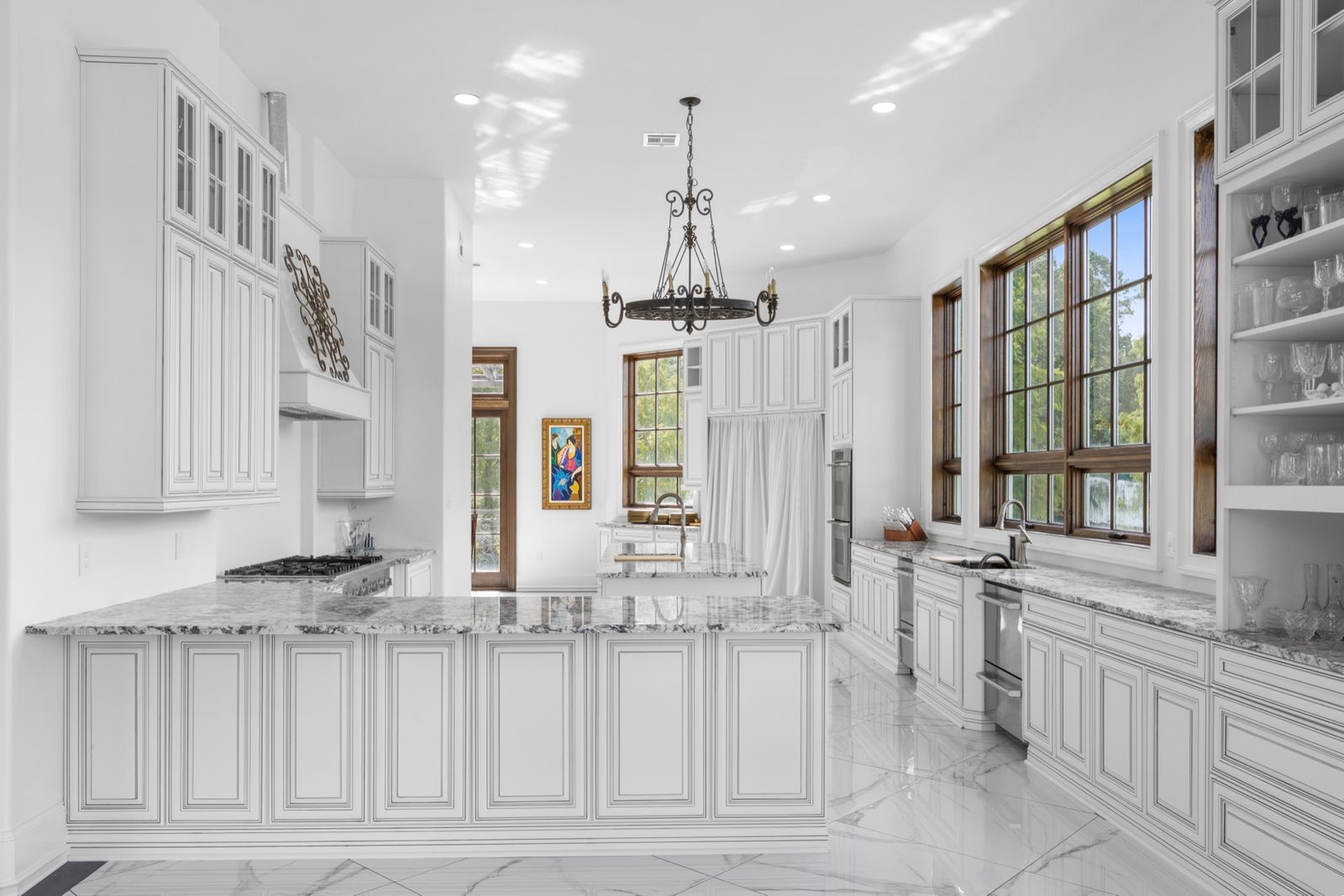 Wide view of a white kitchen with marble counters