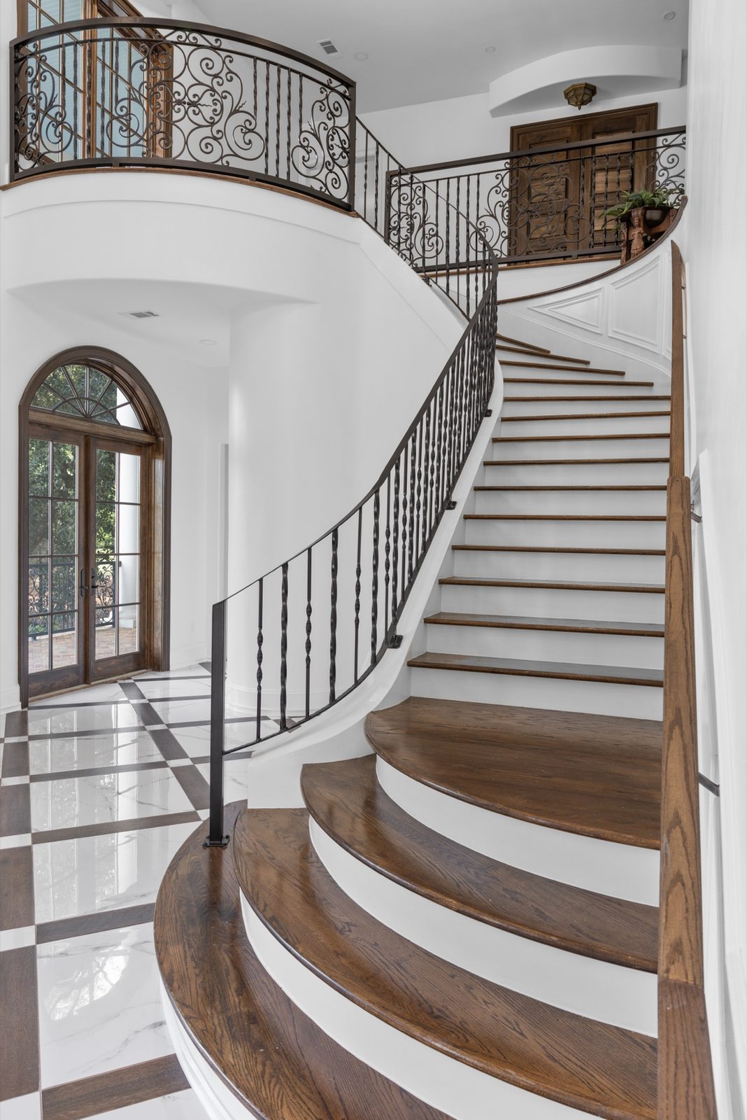 Curved wood staircase with iron balustrade