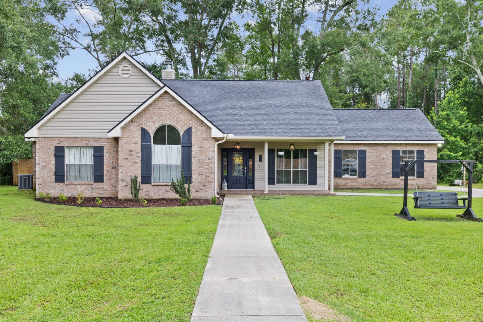 Brick ranch home with a long front walkway on a large green lot